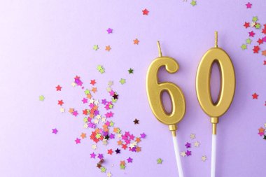 60th birthday. Number shaped candles and confetti on violet background, flat lay