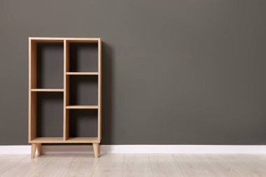 Empty shelving unit near grey wall indoors, space for text