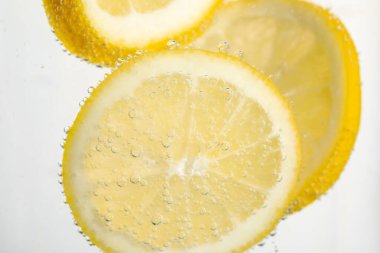 Arka planda limon dilimleri olan soda, yakın plan.