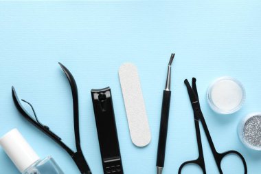 Açık mavi zemin üzerinde farklı manikür araçları kümesi, düz yatıyordu