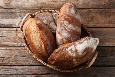 Tahta masadaki sepetin içinde farklı somunlar, üst manzara.