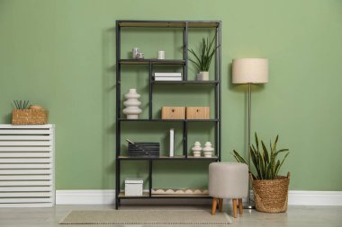 Salon içinde zeytin duvarının yanında farklı dekorasyonu olan ahşap raf ünitesi.