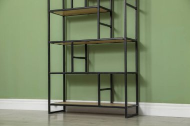 İçerideki zeytin duvarının yanındaki boş ahşap raf ünitesi.