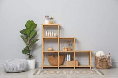 Açık gri duvarın yanında farklı dekorasyona sahip ahşap raf ünitesi.
