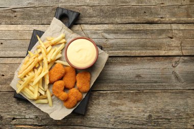 Kasede leziz peynir sosu, tavuk nugget ve ahşap masada patates kızartması, üst manzara. Metin için boşluk