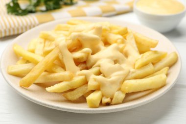 Beyaz ahşap masada peynir soslu patates kızartması, yakın plan.