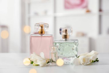 Parfüm şişeleri ve beyaz masada güzel çiçekler.