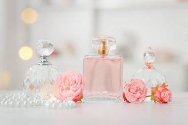 Parfüm şişeleri ve beyaz masada güzel çiçekler.