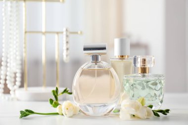 Parfüm şişeleri ve beyaz masada güzel çiçekler.