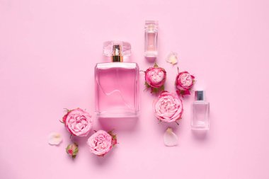 Parfüm şişeleri ve pembe arka planda güzel çiçekler.