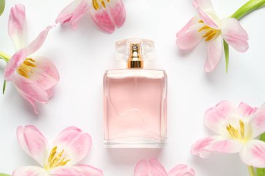 Bir şişe parfüm ve beyaz arka planda güzel çiçekler.