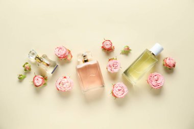 Parfüm şişeleri ve bej arka planda güzel çiçekler.
