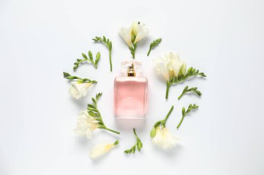 Bir şişe parfüm ve beyaz arka planda güzel çiçekler.