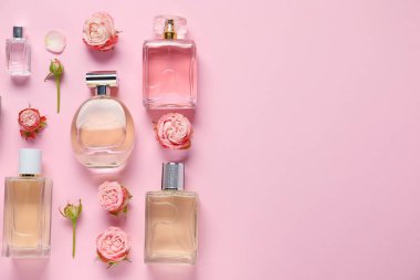 Parfüm şişeleri ve pembe arka planda güzel çiçekler. Metin için boşluk