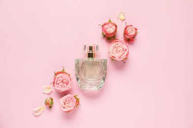 Bir şişe parfüm ve pembe arka planda güzel çiçekler.