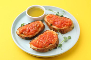 Domatesli lezzetli ekmek, mikroyeşiller ve sarı arka planda yağ, yakın plan.