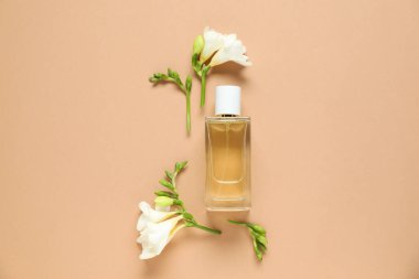 Düz kompozisyon, aromatik parfüm şişesi ve bej arka planda güzel çiçekler.