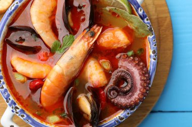 Lezzetli deniz ürünleri çorbası mavi ahşap masada, üst manzara.