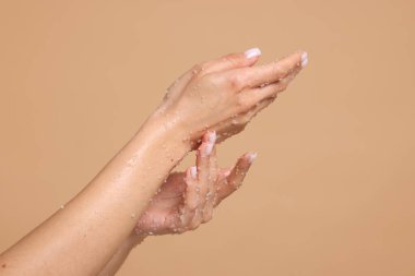 Bej arka planda ellerini ovuşturan kadın, yakın plan.