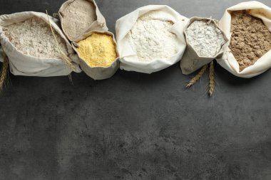 Gri masadaki poşetlerdeki farklı tipte un, düz. Metin için boşluk