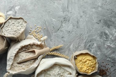 Gri desenli masa ve düz yatak üzerinde farklı tipte un torbaları. Metin için boşluk