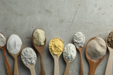 Açık gri masadaki kaşıklarda farklı türde un, düz. Metin için boşluk