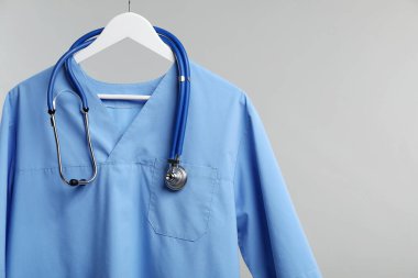 Gri arka planda steteskop takılı sağlık çalışanı üniforması. Metin için boşluk