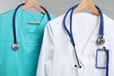 Steteskop ve rozetli sağlık görevlileri gri arka planda, yakın planda.