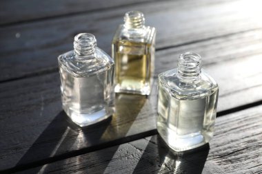 Siyah ahşap arka planda aromatik yağlı parfüm şişeleri, yakın plan.