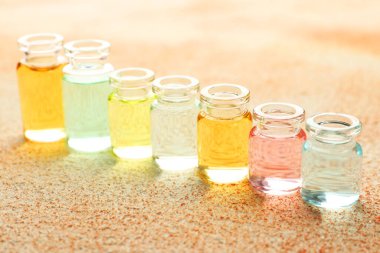 Bej desenli arka planda aromatik yağlı parfüm şişeleri, yakın plan.