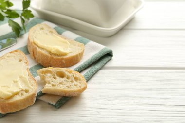 Beyaz ahşap masada tereyağlı ekmek dilimleri, yakın plan. Metin için boşluk