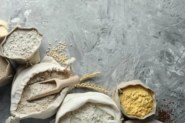 Gri desenli masa ve düz yatak üzerinde farklı tipte un torbaları. Metin için boşluk