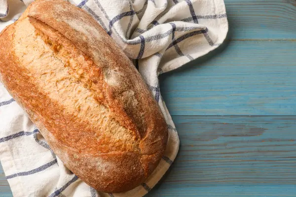 Açık mavi ahşap masada taze ekmek, üst manzara. Metin için boşluk