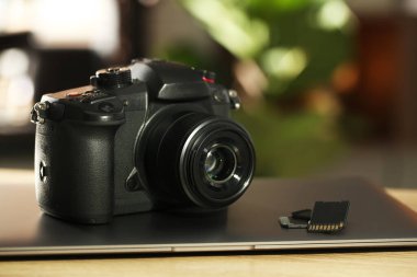 SD hafıza kartları, dizüstü bilgisayar ve fotoğraf makinesi ahşap masada, yakın plan.