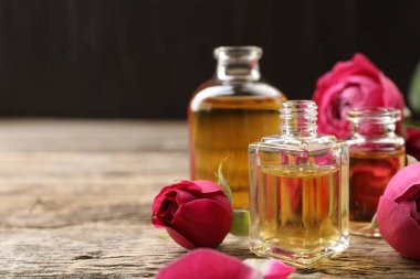 Ahşap masanın üzerinde aromatik esanslı yağlar ve güller olan parfüm şişelerini aç, yakın plan. Metin için boşluk