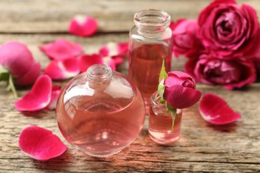 Ahşap masanın üzerinde aromatik esanslı yağlar ve güller olan parfüm şişelerini aç.