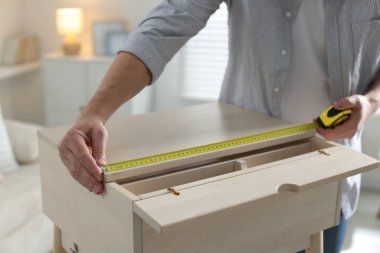 İçerideki bantla ahşap dolabı ölçen adam, yakın plan.