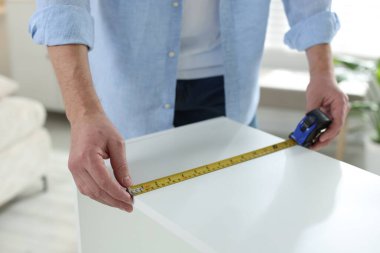 Beyaz rafları bantla ölçen adam içeride, yakın plan.