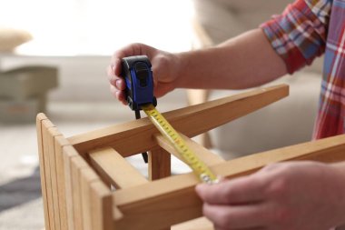 İçerideki bantla ahşap tabureyi ölçen adam, yakın plan.