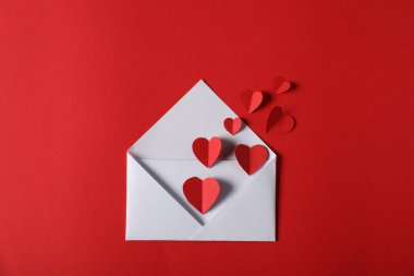 Kırmızı arka planda kağıttan kalpler uçuşuyordu.