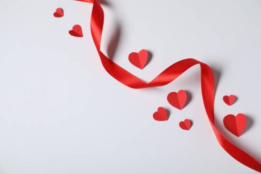 Açık gri arka planda bir sürü kağıt kalp ve kurdele düz yatıyordu. Metin için boşluk