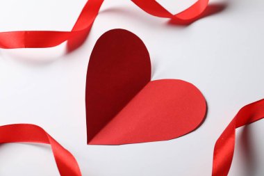 Açık gri arkaplanda bir kağıt kalp ve kurdele, yakın plan.