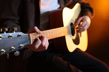 Kahverengi arka planda gitar çalan adam, yakın plan.