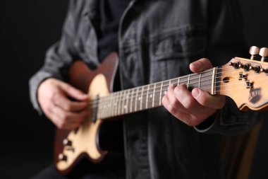 Siyah arkaplanda gitar çalan adam, yakın plan