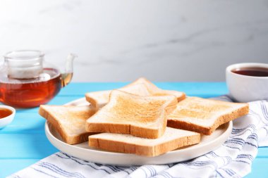 Açık mavi ahşap masada, gri arkaplanda, yakın plan, lezzetli kızarmış ekmek dilimleri.