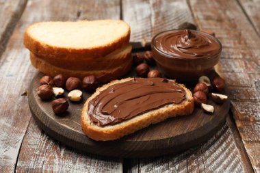 Çikolatalı fındıklı tost ve ahşap masada fındıklar, yakın plan.