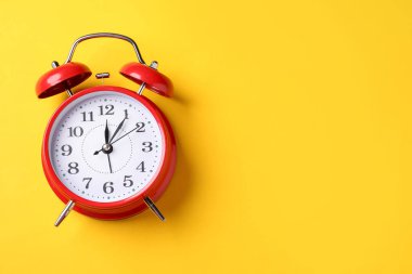 Sarı arka planda kırmızı alarm saati, üst manzara. Metin için boşluk