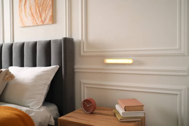 Kapalı bir odada beyaz duvarda parıldayan modern LED lamba.