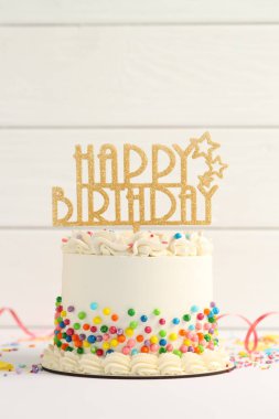 Delicious bento cake with colorful sprinkles, topper and serpentine streamer on white table