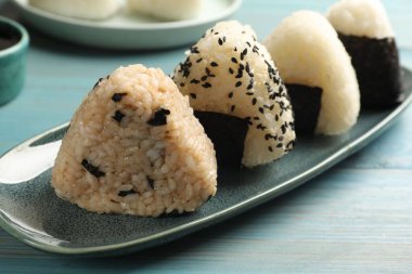 Açık mavi ahşap masada pirinç topları (onigiri), yakın plan. Geleneksel Japon yemeği